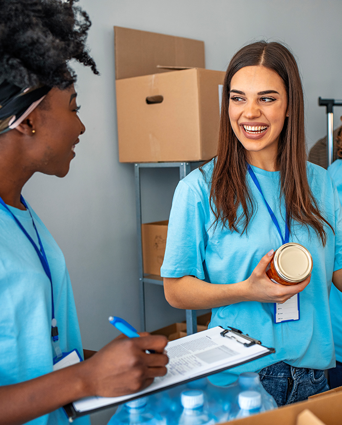 Two female volunteers packing care boxes with food